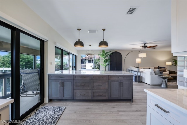 kitchen with ceiling fan with notable chandelier, pendant lighting, light wood-type flooring, and white cabinetry