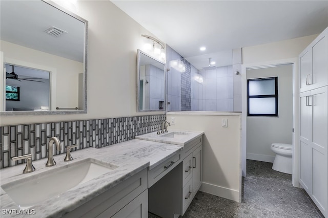 bathroom with backsplash, a tile shower, vanity, ceiling fan, and toilet