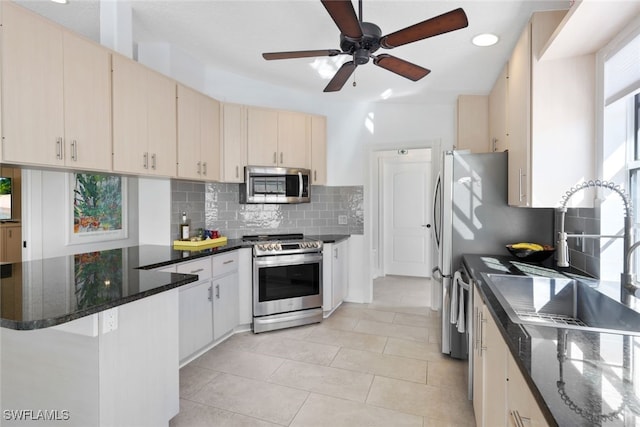 kitchen with backsplash, stainless steel appliances, dark stone counters, and light tile patterned flooring