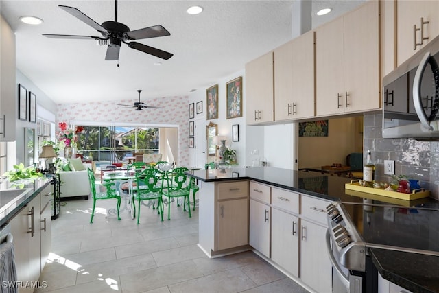 kitchen featuring kitchen peninsula, stove, decorative backsplash, cream cabinets, and light tile patterned flooring