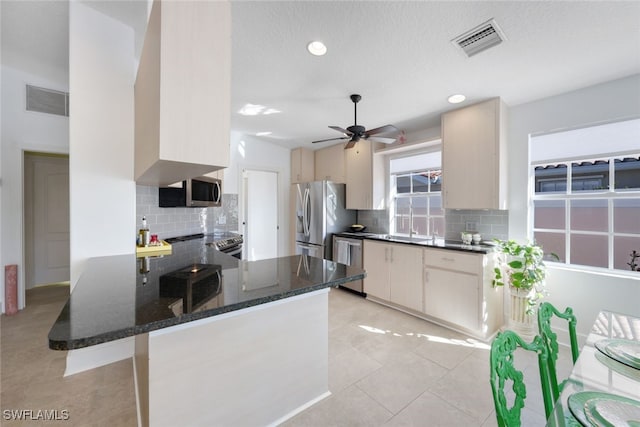 kitchen featuring dark stone counters, sink, decorative backsplash, appliances with stainless steel finishes, and kitchen peninsula