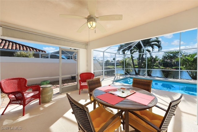 sunroom featuring ceiling fan and a water view