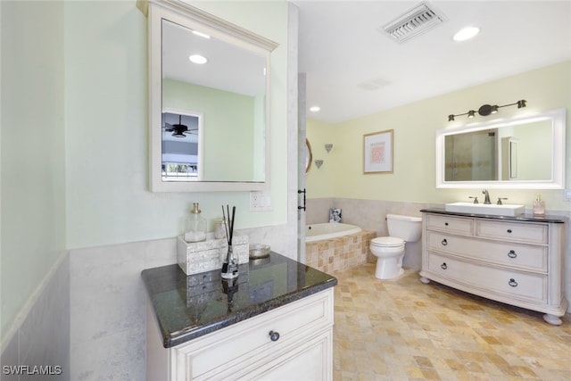 bathroom featuring vanity, ceiling fan, a washtub, toilet, and tile walls