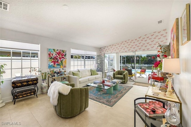 living room featuring tile patterned flooring, visible vents, and wallpapered walls