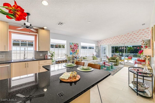 kitchen with a sink, visible vents, ceiling fan, open floor plan, and wallpapered walls
