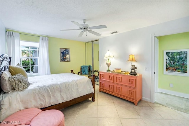 bedroom featuring a ceiling fan, a closet, light tile patterned floors, baseboards, and visible vents