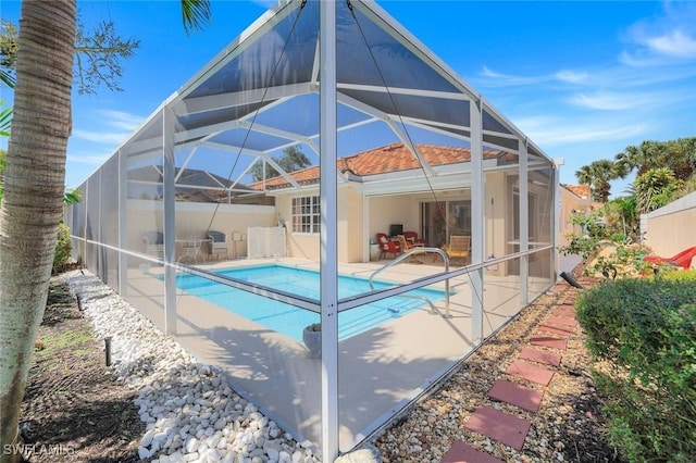 rear view of house with a patio area, stucco siding, an outdoor pool, and glass enclosure