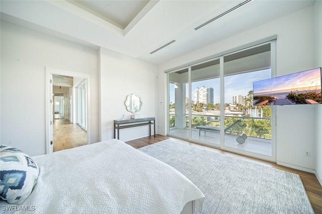 bedroom featuring access to outside, visible vents, and wood finished floors