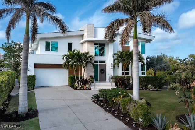 view of front of home with driveway, an attached garage, a front yard, and stucco siding