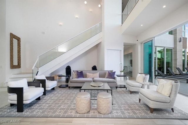 living room featuring stairs, a towering ceiling, and wood finished floors