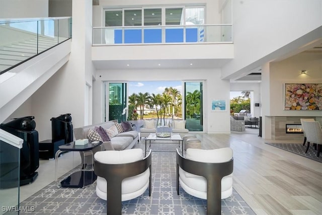 living area with a healthy amount of sunlight, a towering ceiling, wood finished floors, and a high end fireplace