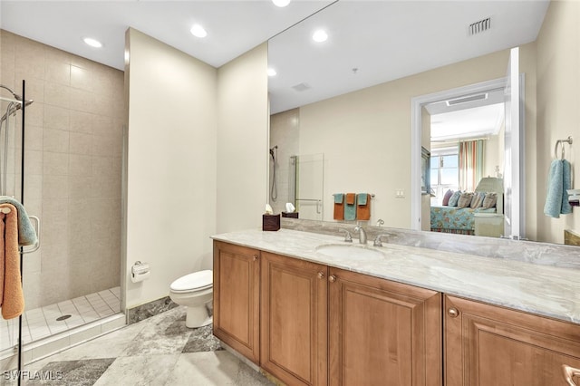 bathroom featuring a tile shower, vanity, and toilet