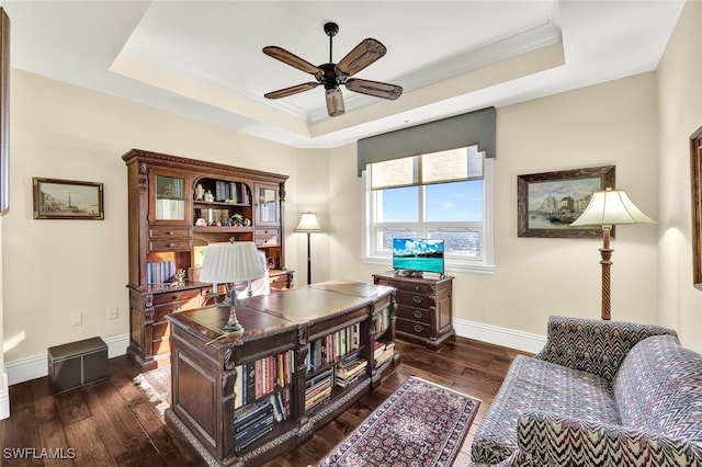 office space with dark hardwood / wood-style flooring, a tray ceiling, ceiling fan, and ornamental molding