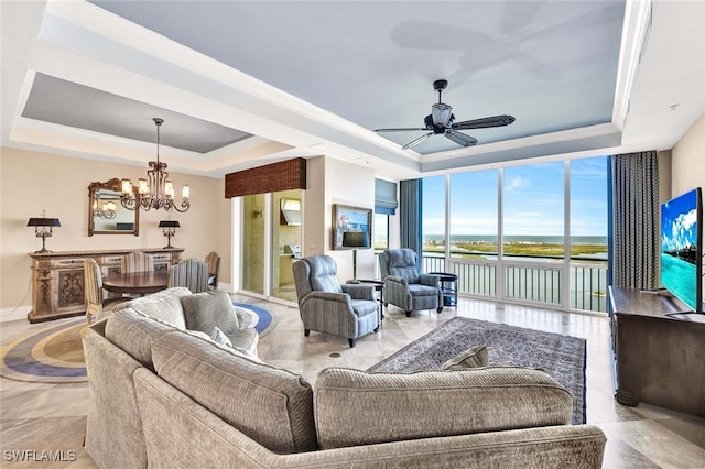 living room with ceiling fan with notable chandelier and a tray ceiling