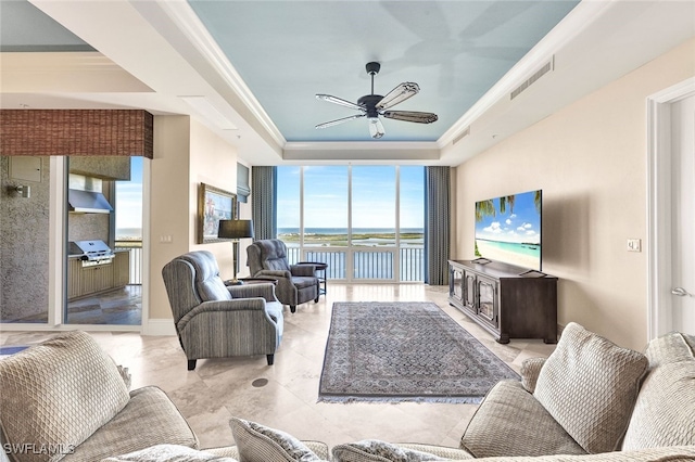 living room featuring ceiling fan, floor to ceiling windows, ornamental molding, and a tray ceiling