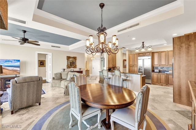 dining space featuring ceiling fan with notable chandelier, a tray ceiling, and ornamental molding