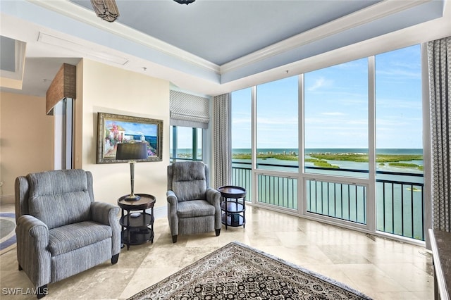 living area featuring a water view, crown molding, a wealth of natural light, and a tray ceiling