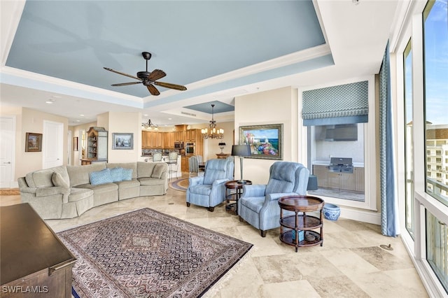 living room featuring ceiling fan with notable chandelier, a raised ceiling, and crown molding