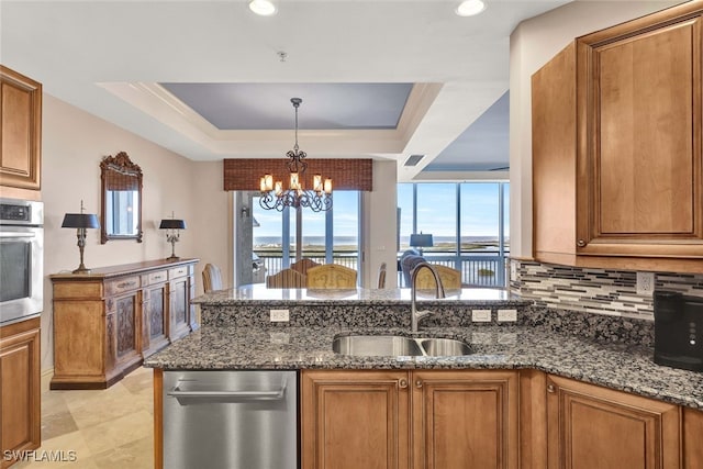 kitchen featuring sink, a notable chandelier, dark stone countertops, a water view, and appliances with stainless steel finishes