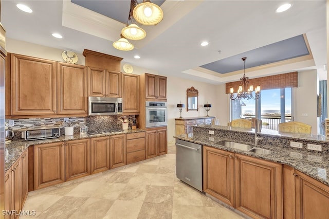 kitchen with stainless steel appliances, a raised ceiling, sink, decorative light fixtures, and an inviting chandelier