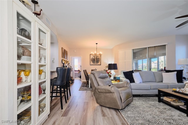 living room featuring ceiling fan with notable chandelier and light wood-type flooring