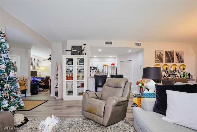 living room with ceiling fan and light hardwood / wood-style flooring