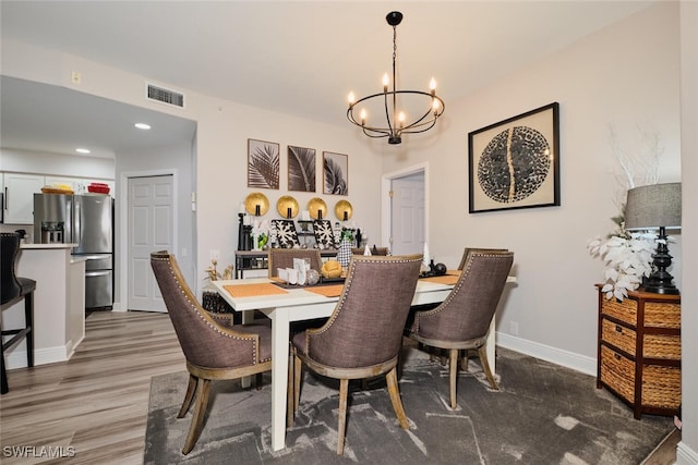 dining space with hardwood / wood-style floors and an inviting chandelier