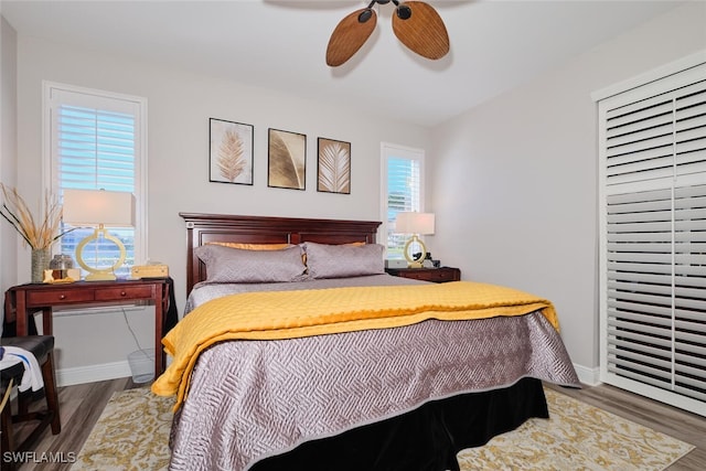 bedroom with ceiling fan, dark hardwood / wood-style flooring, and multiple windows