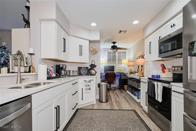 kitchen with white cabinetry, sink, ceiling fan, light hardwood / wood-style floors, and appliances with stainless steel finishes