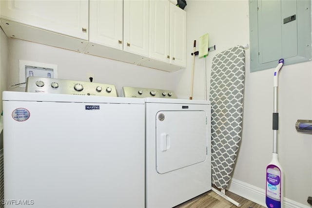 laundry area with electric panel, cabinets, washer and dryer, and wood-type flooring