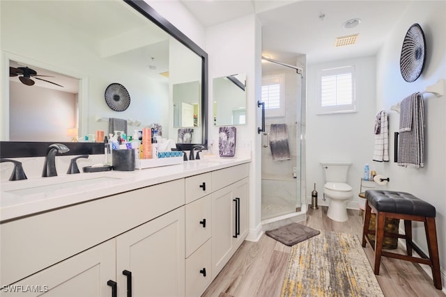 bathroom with vanity, ceiling fan, wood-type flooring, toilet, and a shower with shower door