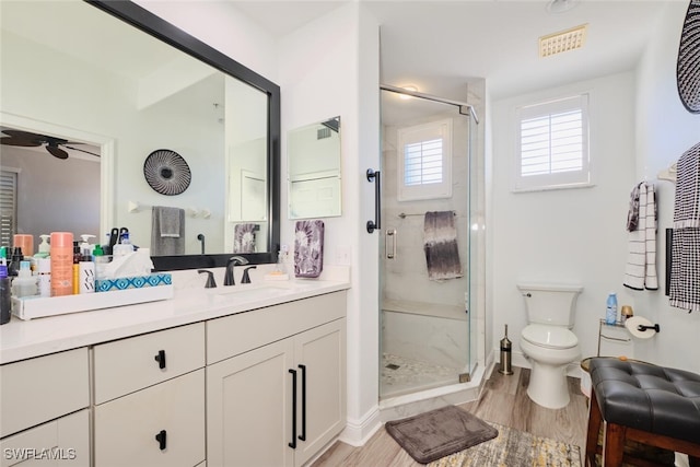 bathroom with hardwood / wood-style floors, toilet, an enclosed shower, and ceiling fan