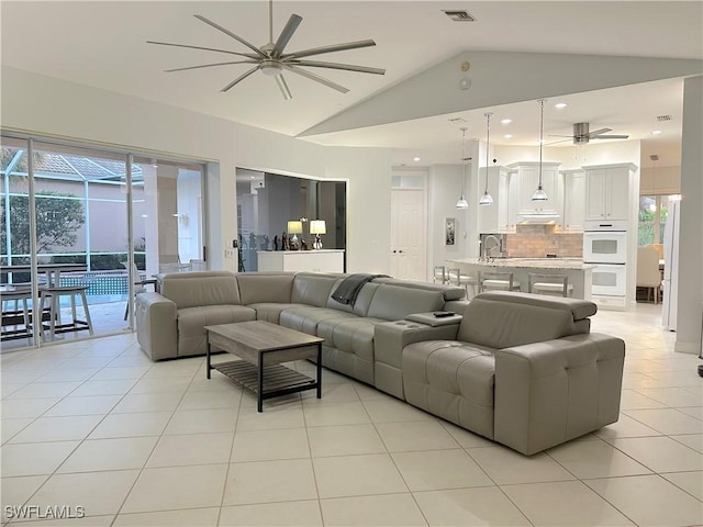 living room featuring light tile patterned floors, vaulted ceiling, ceiling fan, and sink