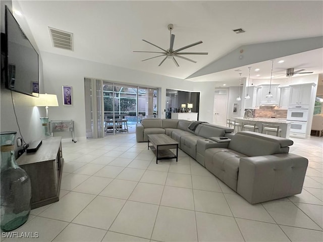 tiled living room featuring ceiling fan, sink, and lofted ceiling