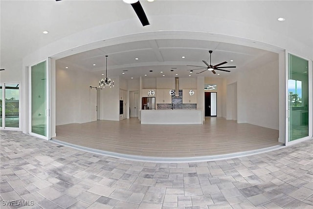 unfurnished living room with ceiling fan with notable chandelier