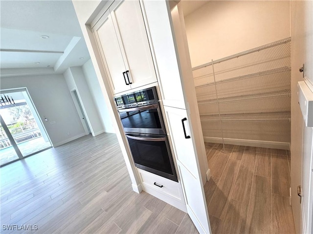 kitchen featuring double oven, light hardwood / wood-style flooring, and white cabinets