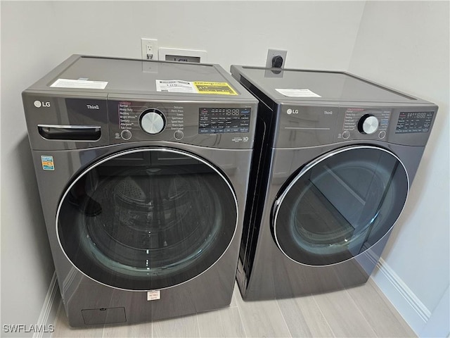 laundry room with wood-type flooring and independent washer and dryer