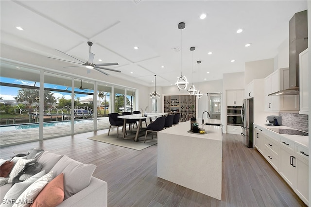 kitchen featuring white cabinets, pendant lighting, stainless steel refrigerator, and a kitchen island with sink