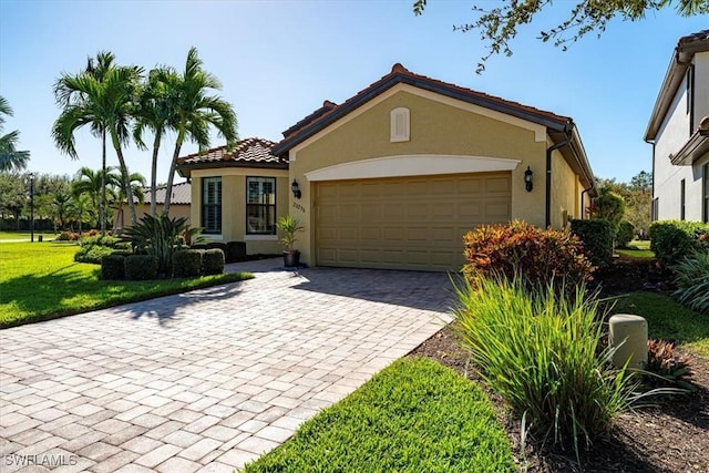 20256 Black Tree Ln, Estero, FL 33928 - view of front of property featuring decorative driveway, a garage, stucco siding, a front lawn, and a tiled roof