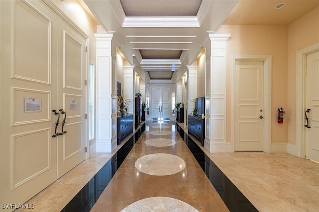 interior space featuring ornamental molding, a tray ceiling, and ornate columns