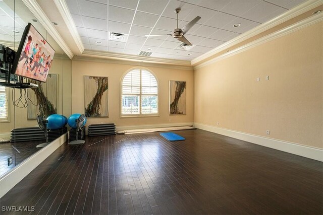 workout room featuring crown molding, a paneled ceiling, ceiling fan, a tray ceiling, and dark hardwood / wood-style flooring