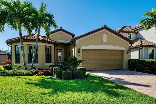 20256 Black Tree Ln, Estero, FL 33928 - mediterranean / spanish house featuring stucco siding, a front lawn, a garage, decorative driveway, and a tile roof