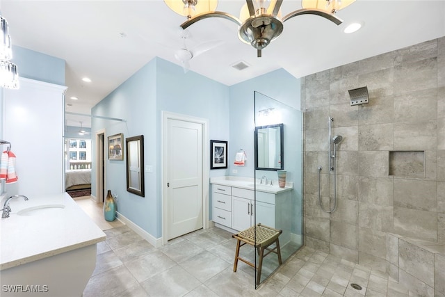 bathroom with a tile shower, vanity, and ceiling fan