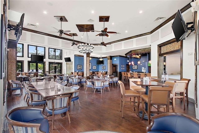 dining area featuring ceiling fan, decorative columns, a towering ceiling, wood-type flooring, and ornamental molding