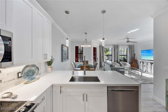 kitchen with decorative backsplash, stainless steel appliances, ceiling fan, sink, and white cabinetry