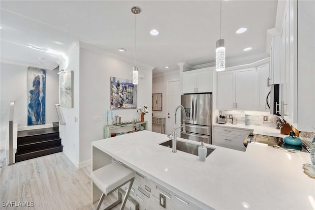 kitchen with white cabinetry, light hardwood / wood-style flooring, pendant lighting, a kitchen bar, and appliances with stainless steel finishes