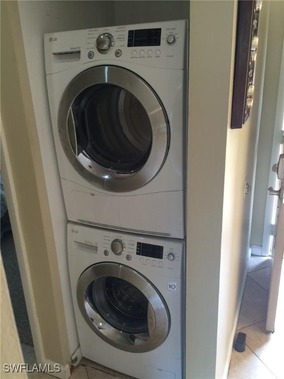 washroom featuring light tile patterned flooring and stacked washing maching and dryer