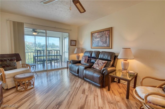 living room with a textured ceiling, light hardwood / wood-style floors, and ceiling fan