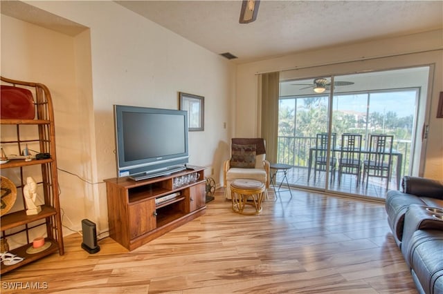 living room featuring a textured ceiling, light wood-type flooring, and ceiling fan