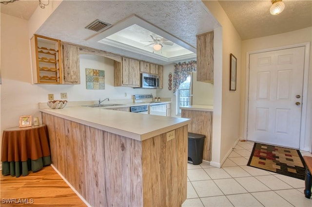 kitchen featuring electric range, kitchen peninsula, a textured ceiling, and light tile patterned floors